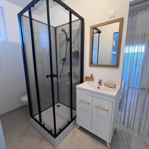 a bathroom with a glass shower and a sink at Cocon avec spa in Mios