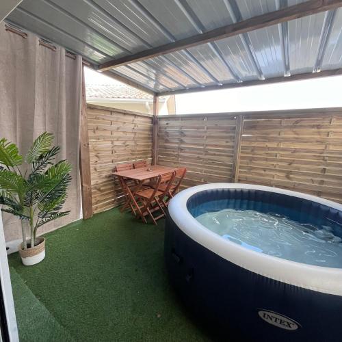 a hot tub on a patio with a table at Cocon avec spa in Mios