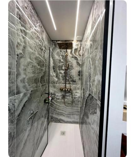 La salle de bains est pourvue d'une douche et de carrelage en marbre gris. dans l'établissement Chambre confort, à Merpins