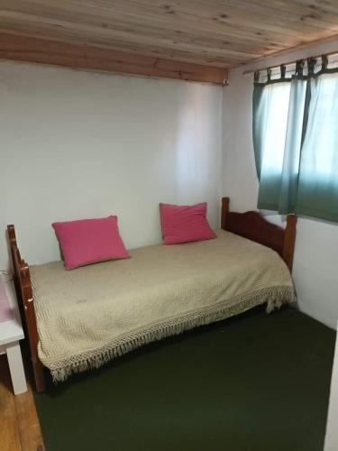 a bed with two pink pillows in a room at El Campito in Necochea