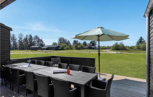 eine Holzterrasse mit Tisch und Sonnenschirm in der Unterkunft Beautiful Home In Hjørring With Sauna in Hjørring