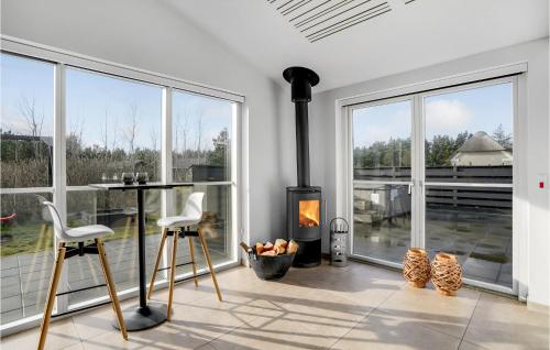 a living room with a fireplace and large windows at Awesome Home In Blåvand With Sauna in Blåvand