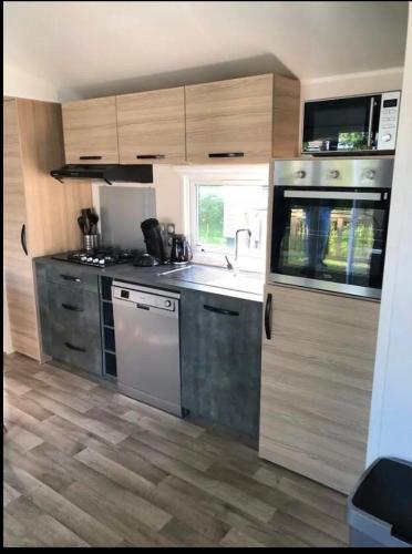 a kitchen with stainless steel appliances and wooden cabinets at Chalet tussen Zee en Meer in Lauwersoog