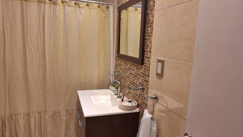 a bathroom with a sink and a shower with a mirror at Casa familiar con doble patio, cochera, fácil acceso en el centro de Escobar in Belén de Escobar