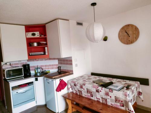 Elle comprend une petite cuisine équipée d'un réfrigérateur blanc et d'une table. dans l'établissement F2 front de neige la Rosière, à La Rosière
