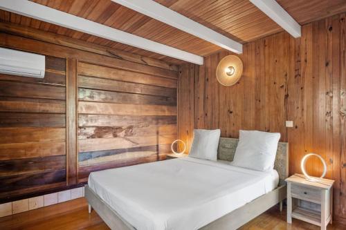 a bedroom with a white bed and wooden walls at Chalet Jujube - Magnifique cottage avec piscine in Les Anses-dʼArlets
