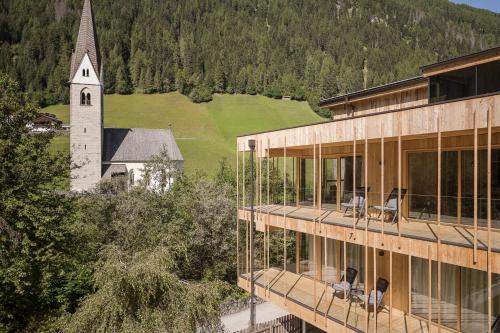 a building with chairs on the balcony with a church at Naturhotel Rainer in Racines