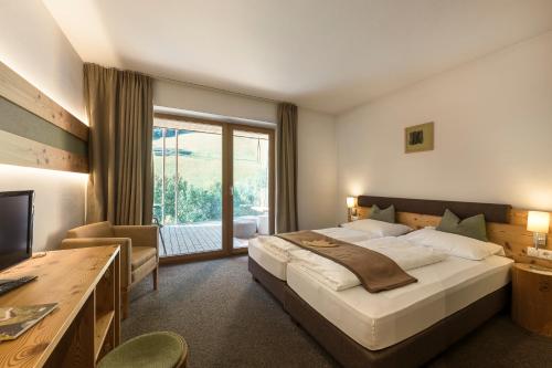 a bedroom with a large bed and a large window at Naturhotel Rainer in Racines