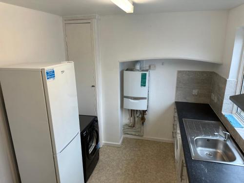 a small kitchen with a refrigerator and a sink at Shouth Harrow in Harrow on the Hill