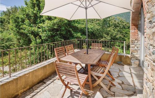 d'une table et de chaises en bois avec un parasol sur le balcon. dans l'établissement Beautiful Home In Santa Maria Poggio, à Santa-Maria-Poggio