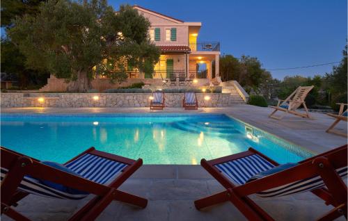 a swimming pool with two chairs in front of a house at 4 Bedroom Awesome Home In Lun in Lun