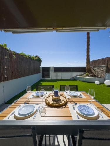 Una mesa de madera con platos y copas de vino encima. en Apartamento en la playa, en Castelldefels