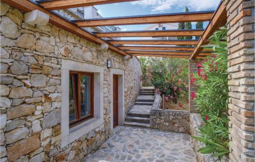 a stone building with a wooden pergola at Pet Friendly Home In Sveti Jakov in Sveti Jakov