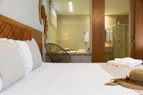 a bedroom with a white bed with a chair and a mirror at Pousada Timoneiro in Vila Velha