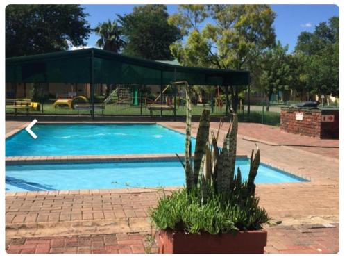 a swimming pool with a green canopy and a playground at 27 Pendleberry Grove, Chris Hani Drive, Bela-Bela in Bela-Bela