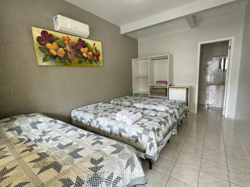 um quarto com duas camas e uma pintura na parede em Pousada na Lagoa da Conceição Barcelos em Florianópolis