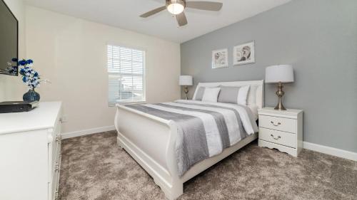 a white bedroom with a bed and a ceiling fan at La Casista in Orlando