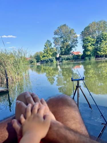 a man laying on a boat on a lake with his feet at Füzesem Apartman in Békésszentandrás