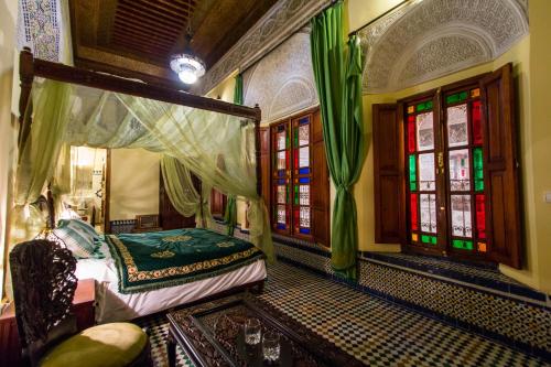 a bedroom with a bed in a room with windows at Riad Ibn Khaldoun in Fez