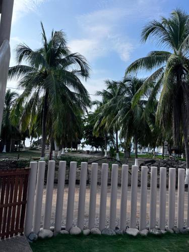 a white fence with palm trees in the background at Villas Cononda in La Majahua
