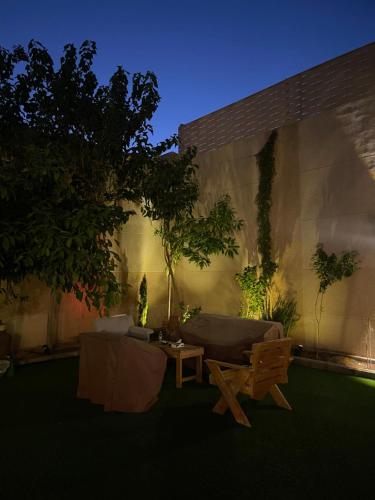 a patio with a couch and a table and trees at Royal AlUla Villa in AlUla