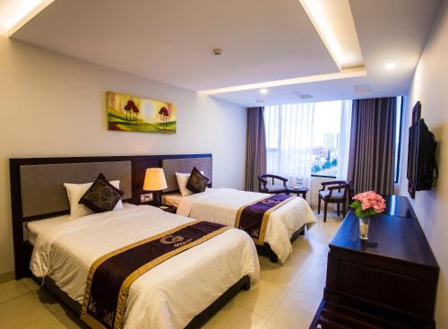 a hotel room with two beds and a table with flowers at Golden Quang Tri Hotel in Ðông Hà