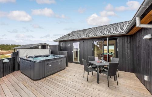 a deck with a hot tub and a table and chairs at Nice Home In Hvide Sande With Sauna in Bjerregård