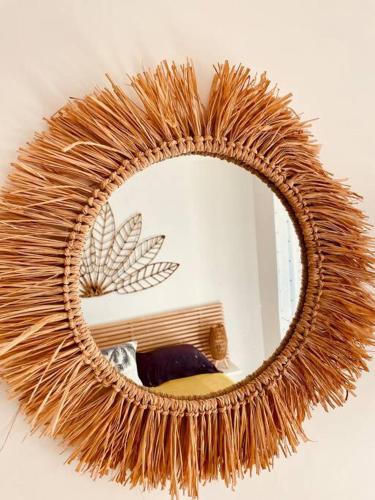 a large rattan mirror with a cat in front of it at Orient Bay Ti Bohème à 2mn de la plage in Orient Bay