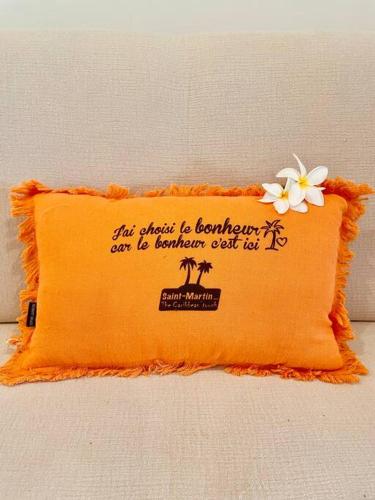 an orange pillow with a flower on top of it at Orient Bay Ti Bohème à 2mn de la plage in Orient Bay