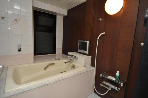 a bathroom with a bath tub with a tv on the wall at Hotel Boston Club (Adult Only) in Tokyo