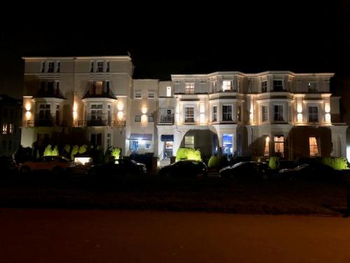 a large white building with its lights on at night at The Carlton Hotel in Folkestone