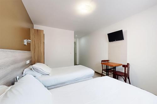 a hotel room with two beds and a table at Hôtel de Ménilmontant in Paris