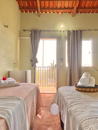 a room with two beds and a large window at Pousada Ondas do Vento in Tatajuba