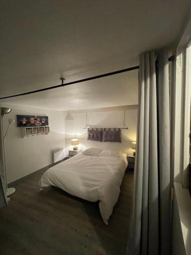 - une chambre avec un grand lit blanc et des rideaux dans l'établissement Plage et commerces à 50m, sans télé pour déconnecter !, à Houlgate
