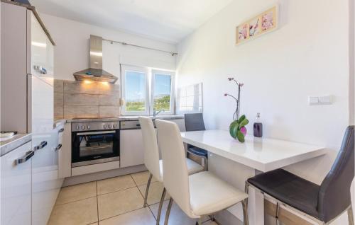 eine Küche mit einer weißen Theke sowie einem Tisch und Stühlen in der Unterkunft Amazing Apartment In Zrnovnica in Korešnica