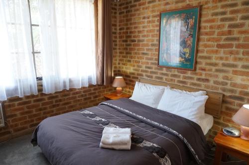 1 dormitorio con 1 cama con pared de ladrillo en Mahogany Park, en Cranbourne