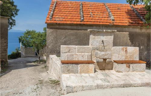 a stone building with two benches in front of it at Two-Bedroom Holiday Home In Tucepi in Tučepi