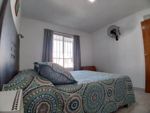 una camera da letto con un letto con una coperta e una finestra di RUTAC DEPARTAMENTOS- Departamento moderno con balcón a Las Grutas