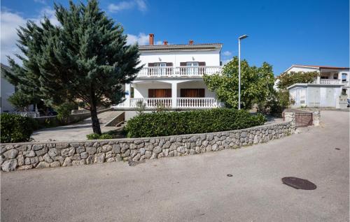 a white house with a stone retaining wall at 1 Bedroom Amazing Apartment In Krk in Krk
