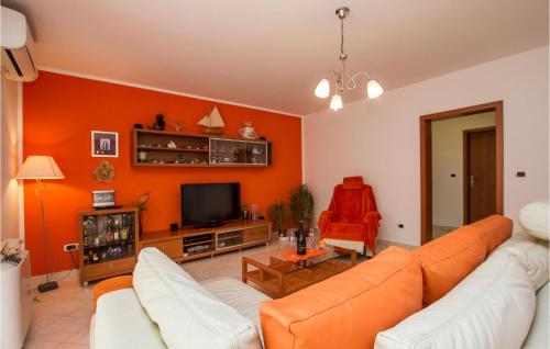 an orange living room with a couch and a tv at Apartment Nedescina Brnjci in Santalezi