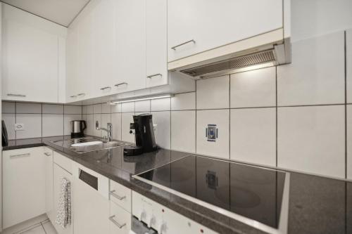 a kitchen with white cabinets and a sink at Pearlstay - City Center Workplace Balcony Washer in Winterthur