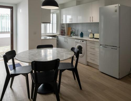 Una cocina con mesa y sillas y un refrigerador. en Casa do Torres, en Évora