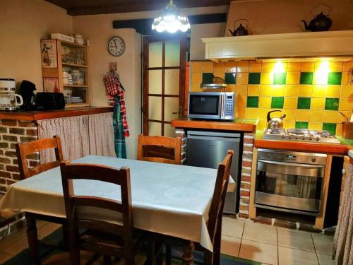 a kitchen with a table and a stove and a microwave at Gîte du Domaine des Garde-Bousset in La Cellette