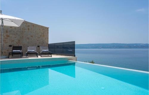 a swimming pool with two chairs next to the water at Pet Friendly Home In Omis With Sauna in Omiš