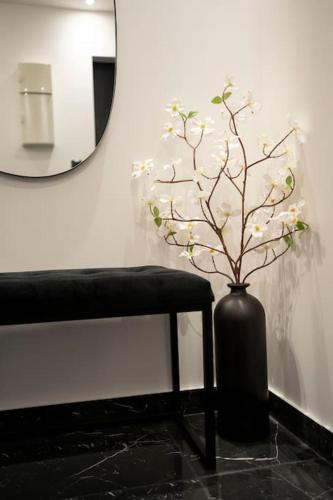 a black vase with a plant in it next to a mirror at Love Room, Luna Spa in Saint-Ouen-lʼAumône