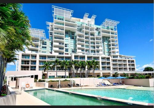 a large building with a swimming pool in front of a building at Golfer's Paradise - Pelican Waters in Pelican Waters