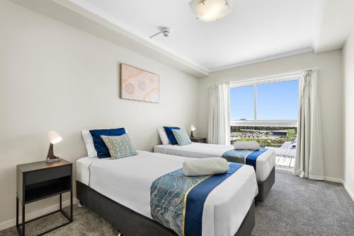 two beds in a room with a window at Golfer's Paradise - Pelican Waters in Pelican Waters