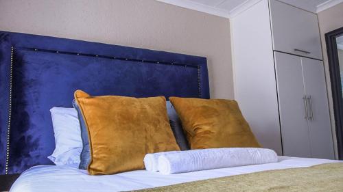 a bed with gold pillows and a blue headboard at Nsuku Guest House in Phalaborwa