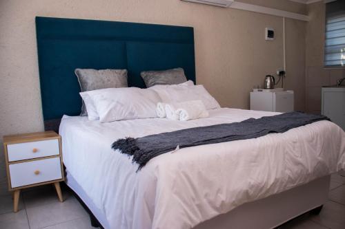 a large bed with white sheets and a blue headboard at Nsuku Guest House in Phalaborwa