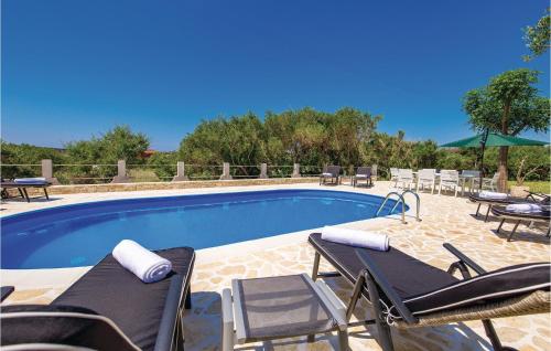 a swimming pool with chaises and chairs next to at 2 Bedroom Gorgeous Apartment In Barbat in Barbat na Rabu